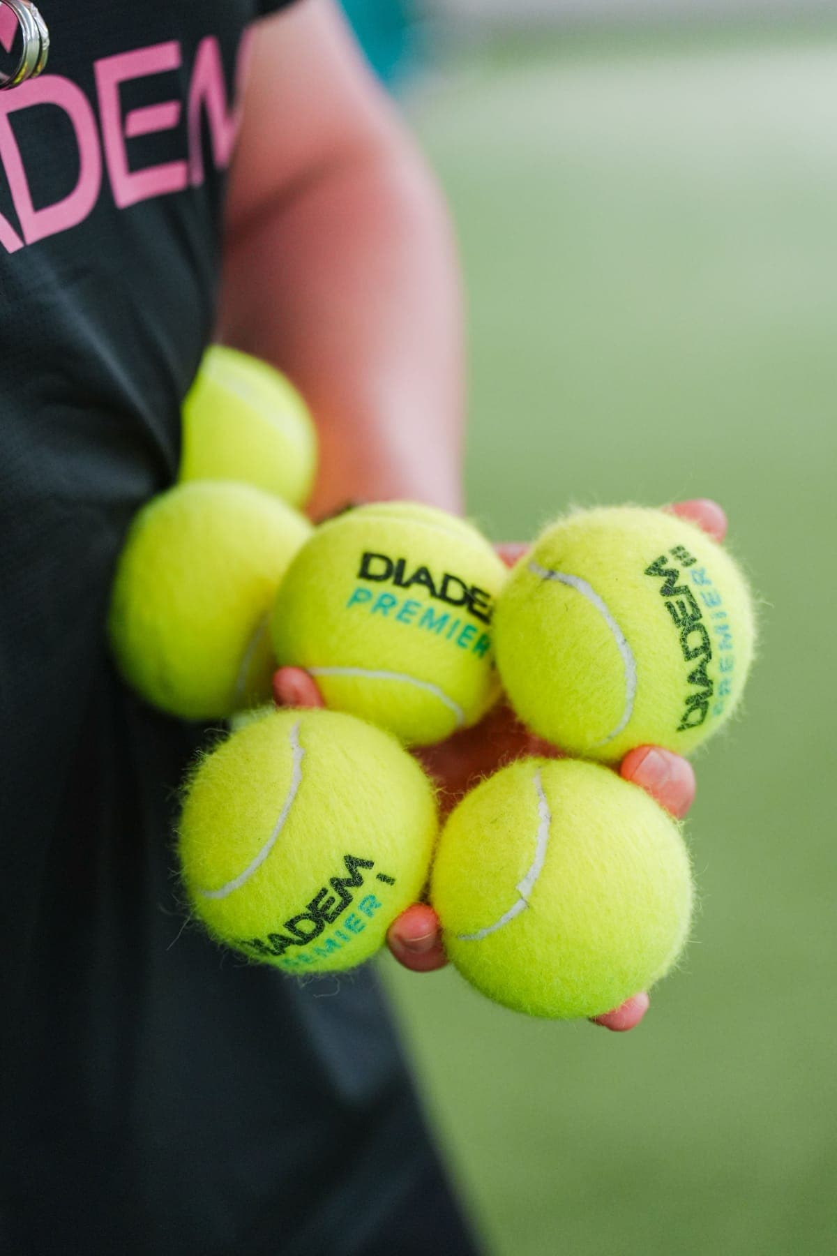 A hand holding five Diadem Premier tennis balls