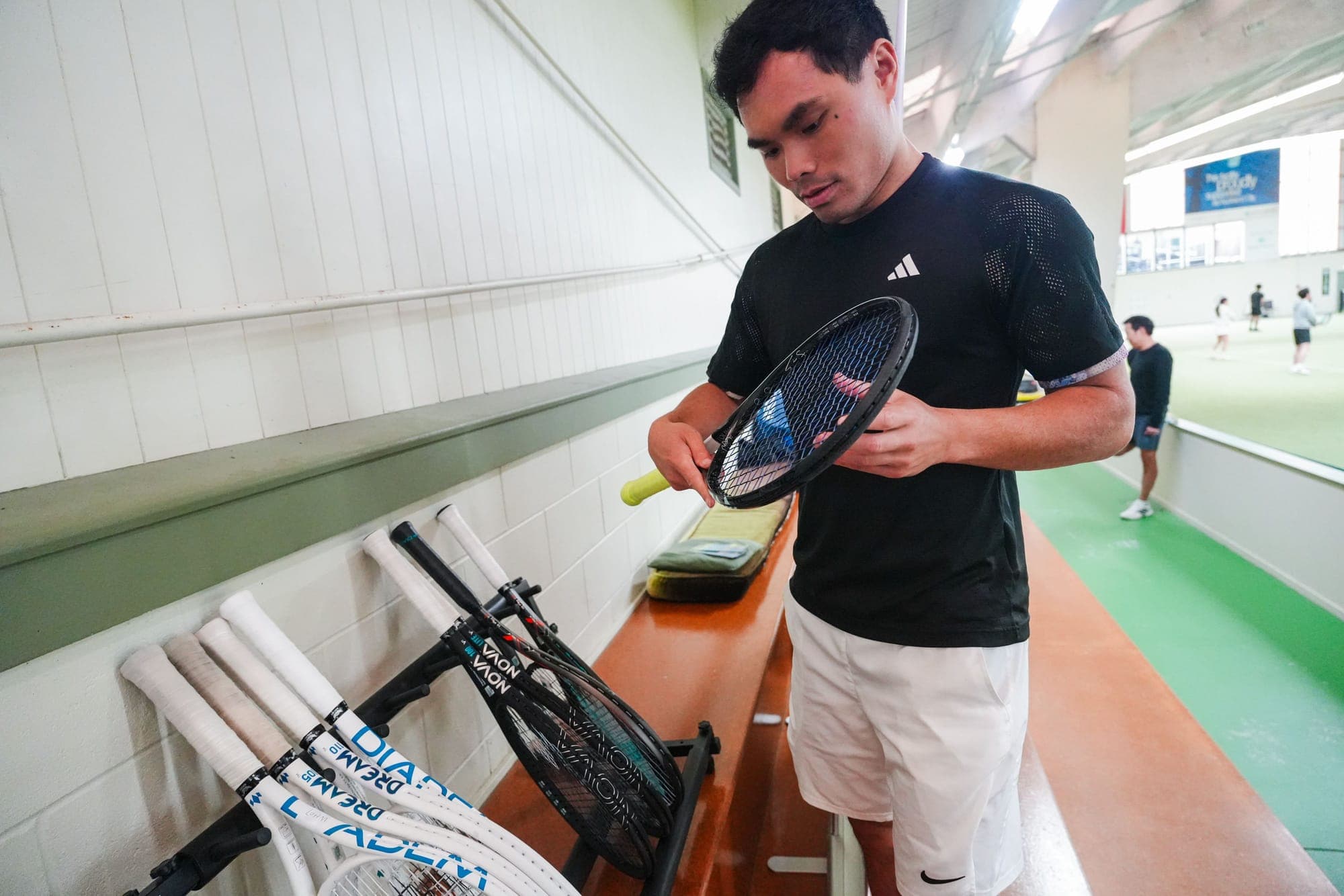 A player checking a Diadem racket beside the demo racket stand