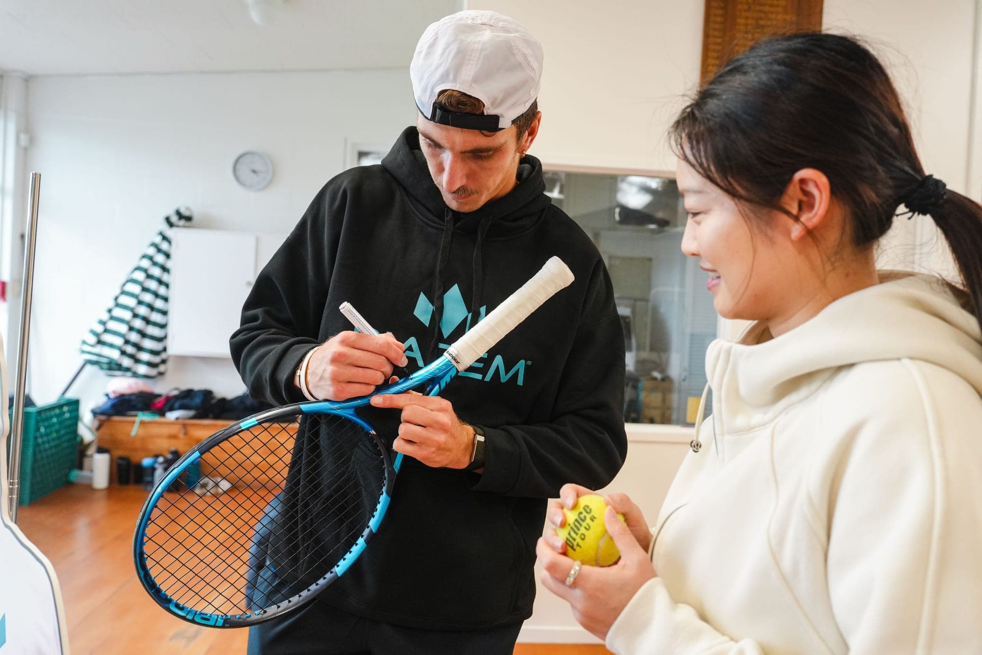 Anton signing a racket grip, with a ball waiting to be signed
